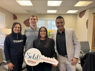 Four people celebrating with a Sold sign.