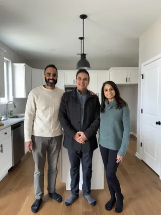Three people smiling together in a bright kitchen.