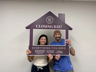 A couple posing with a closing-day photo frame.