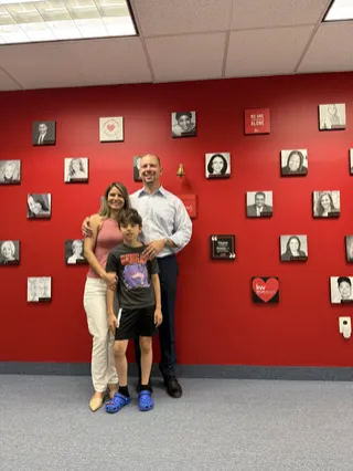 A family portrait in front of a red photo wall.
