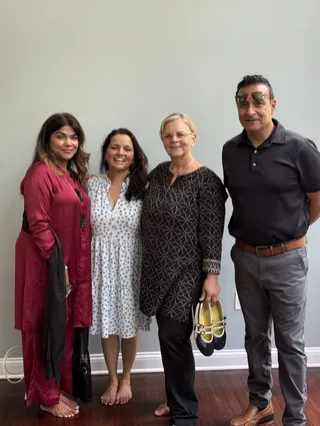 Four people smiling together indoors.