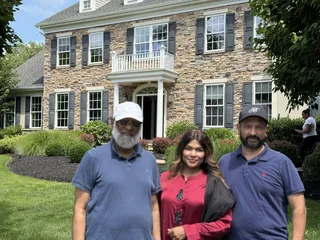 Three people smiling outside a home.