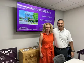 Two people beside a congratulations display.