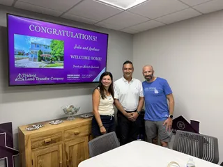 Three people celebrating beside a congratulations display.