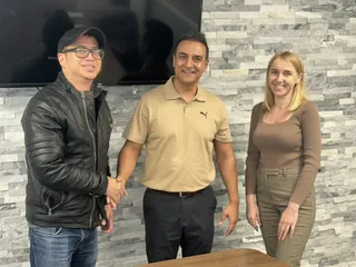 Three people sharing a handshake in an office.
