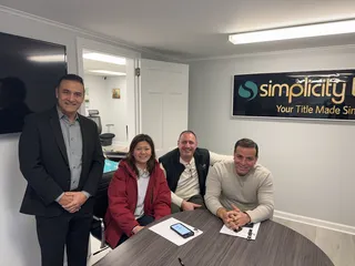 Four people smiling together at a meeting table.