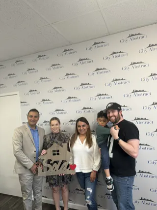 A family celebrating with a Sold backdrop.