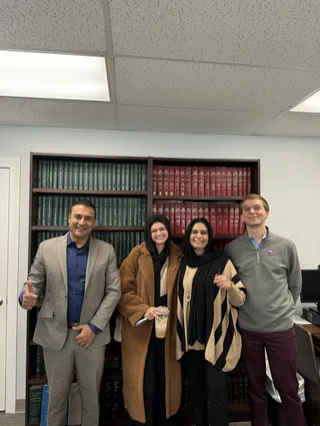 Four people in a room with bookshelves.