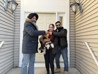 Three people and a dog on a porch.