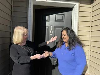 Two people sharing a key handoff by a front door.