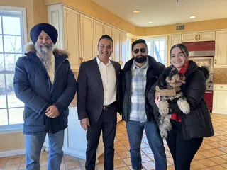 A group and a dog together in a bright kitchen.