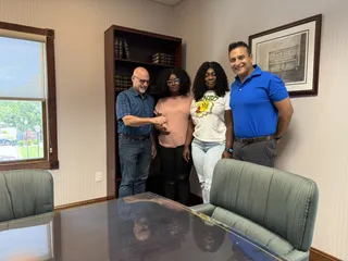 Four people smiling in a meeting room.