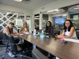 Four people smiling together around a meeting table.