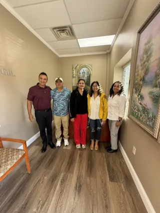 Five people smiling together in an office.
