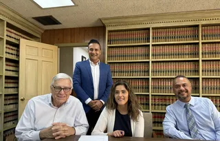 Four people smiling together at a meeting table with bookshelves behind them.