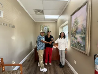 Three people smiling during a key handoff in an office.