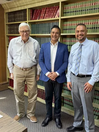 Three people smiling in front of bookshelves.