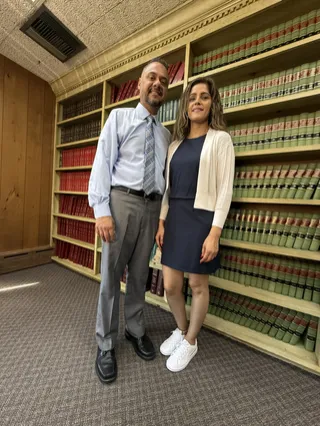 Two people posing together in front of bookshelves.