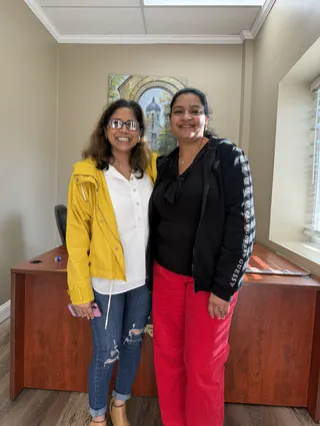 Two people smiling together in a bright office.