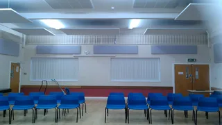 Blue chairs beneath suspended ceiling panels and wall panels at Deepings Community Centre.