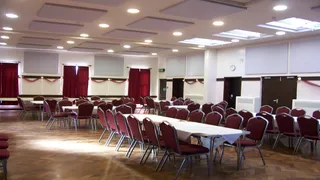 Wall and ceiling panels above tables and burgundy chairs at Worthen Village Hall.