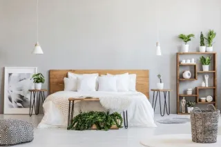 Modern minimalist bedroom design with wooden headboard, white bedding, hanging pendant lights, and decorative shelving, epitomizing timeless home renovation and design.