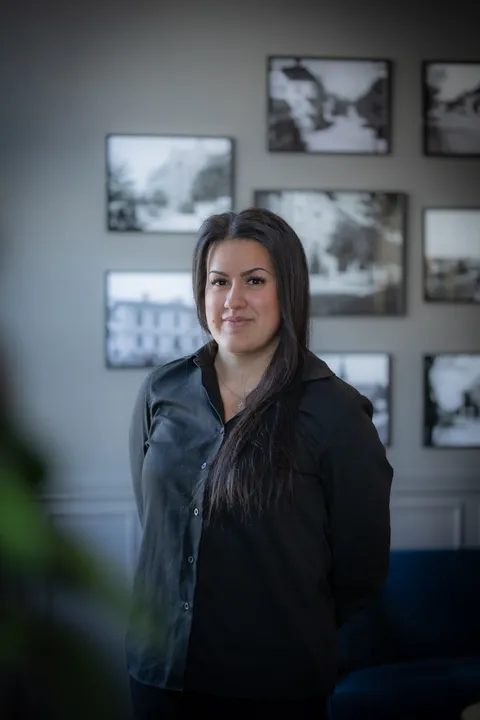 Porträtt av drift- och eventansvarig framför en vägg med svartvita fotografier