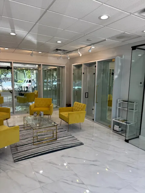 Yellow lounge chairs beside a row of glass shower enclosure displays