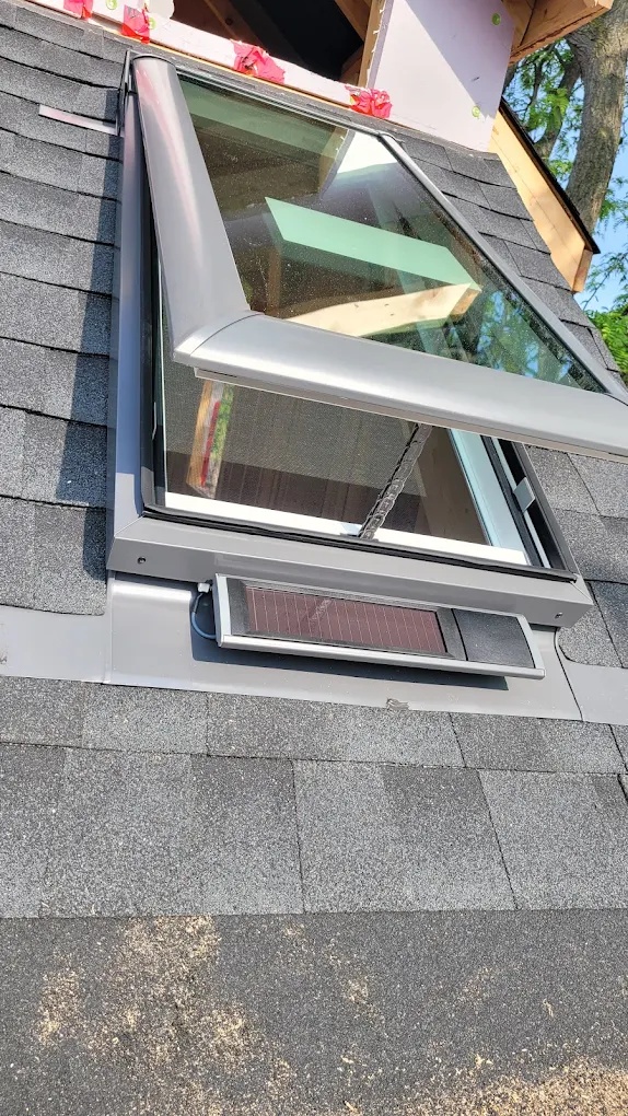 Solar-powered venting Velux skylight installed on a shingle roof for energy-efficient ventilation