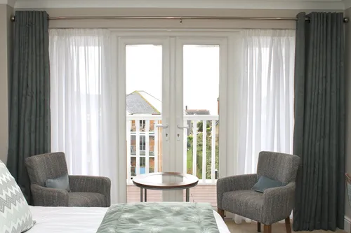 Suite with French doors onto the balcony and two armchairs at The Fig Tree, Shanklin