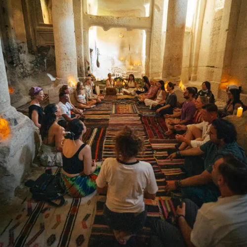 A circle seated on carpets in a cave hall