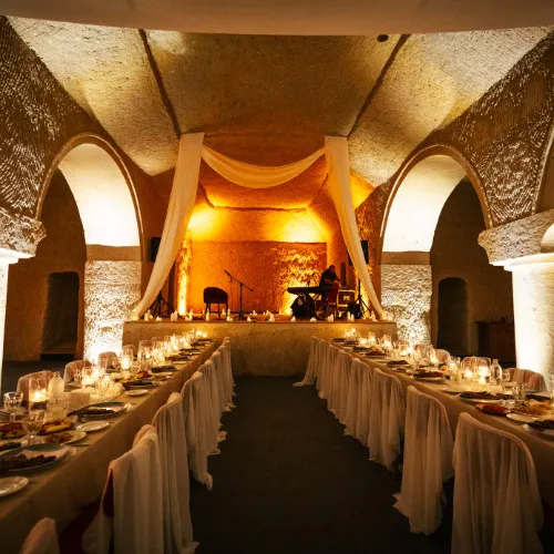 A candlelit dinner table in a vaulted hall