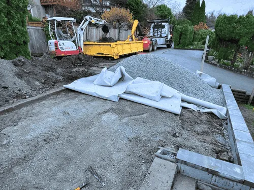Gravel base and fabric laid out for a patio with a mini excavator nearby