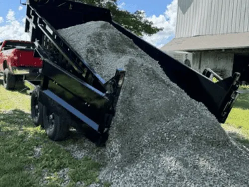 Black dump trailer unloading a pile of gravel