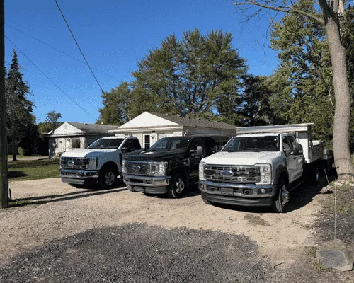Three work pickup trucks parked in a gravel lot