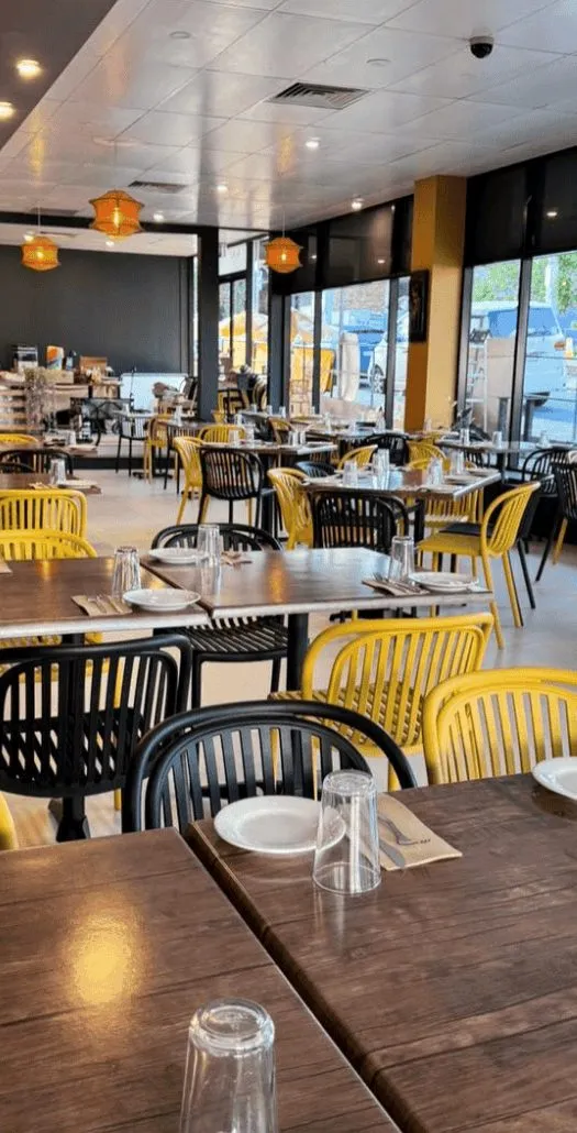 The Walkway to Ceylon dining room with timber tables and yellow chairs