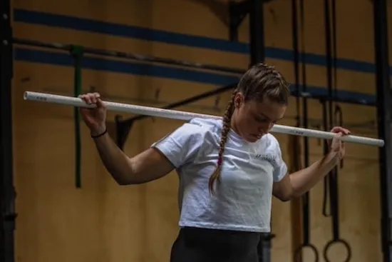 A new member learning the back squat with a PVC pipe