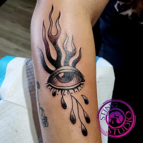 Flaming crying eye flash tattoo by Derrick at Sting Studio Ottawa