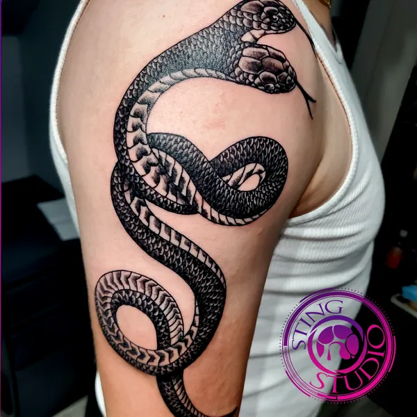 Coiled snake blackwork upper-arm tattoo – Sting Studio Ottawa