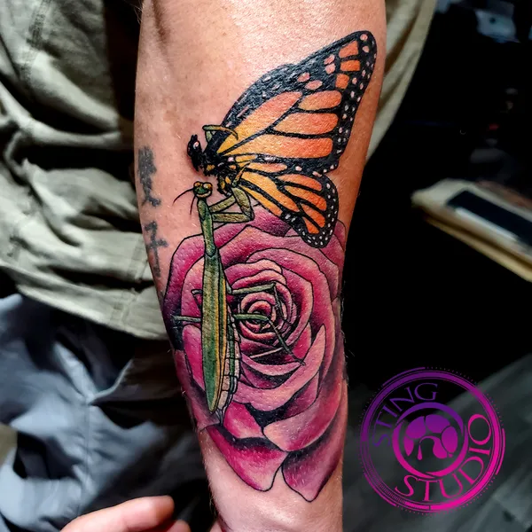 Praying mantis eating butterfly on rose tattoo by Derrick at Sting Studio Ottawa