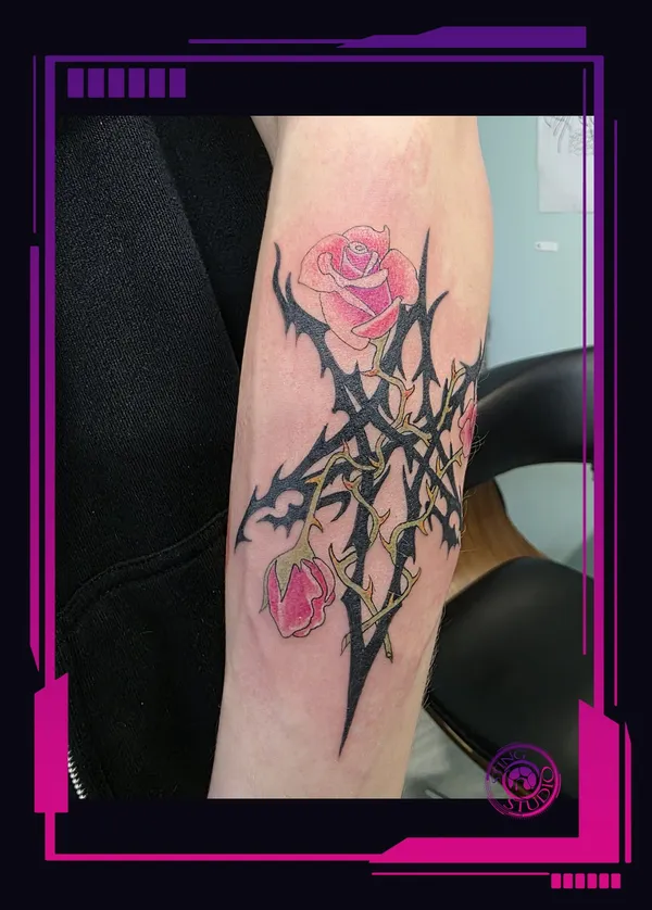 Neo-traditional forearm tattoo of a black thorn pentagram sigil wrapped in golden vines with two pink roses, fresh, by Sting Studio Ottawa.