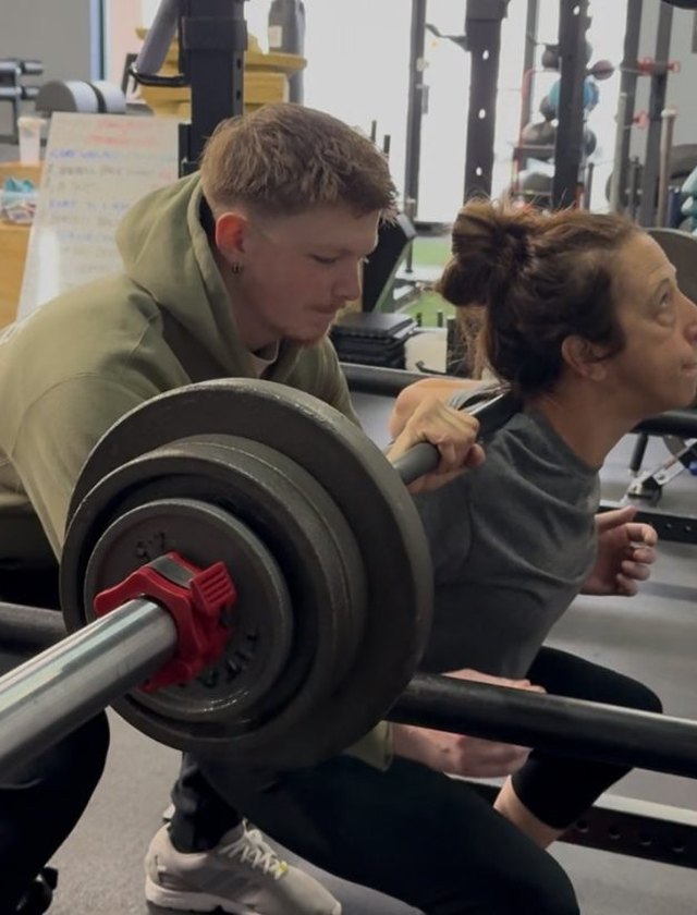 A coach setting up a member at the rack
