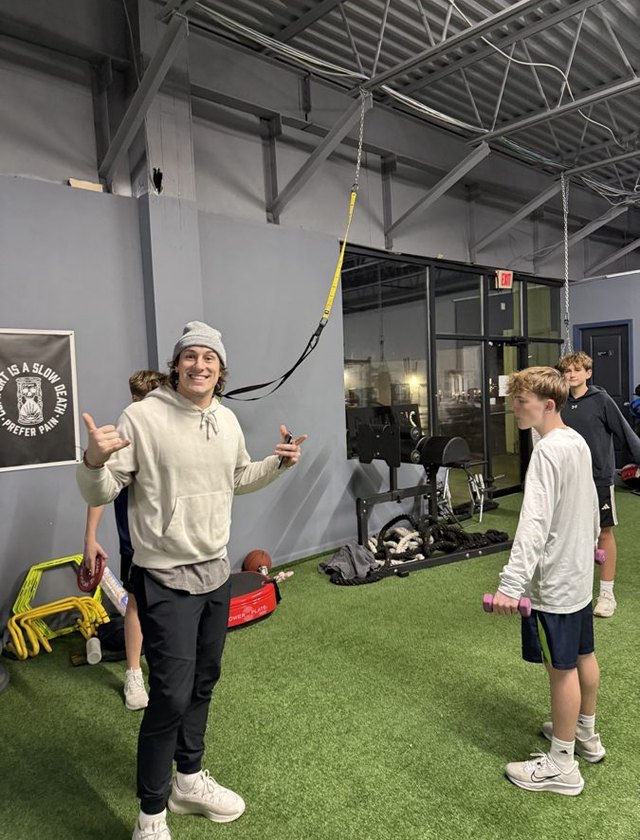 A coach with teen athletes on the straps