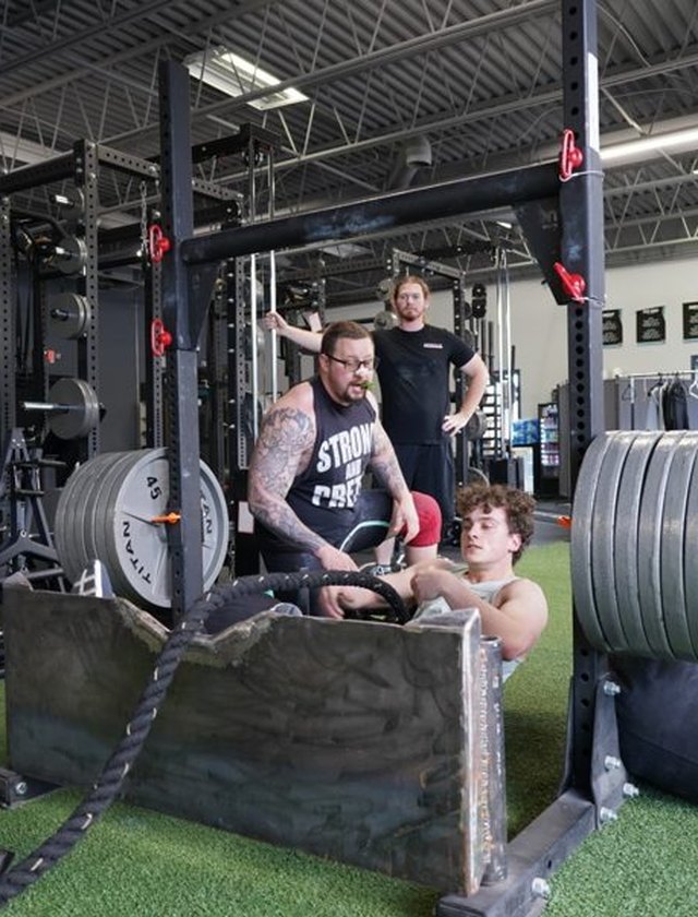A coach and a teen athlete on the trap bar