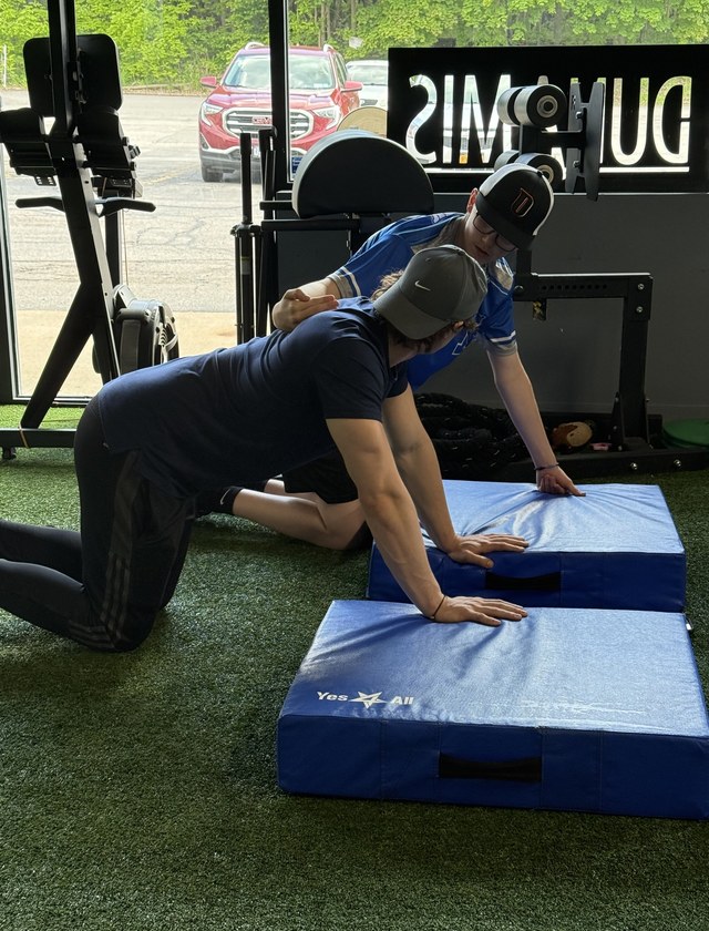 A coach teaching a young athlete the bear crawl
