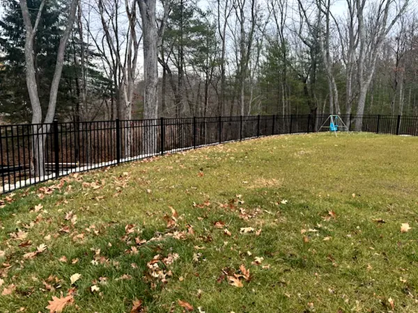 Black aluminum fence following a curved backyard lawn by All Fenced In
