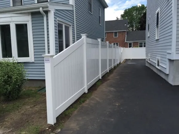 White vinyl privacy fence along a driveway by All Fenced In