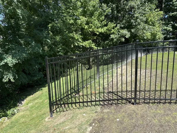 Black fence stepping down a steep grassy hillside by All Fenced In