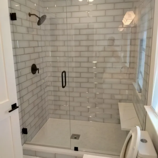 Frameless single-door shower glass with black hardware, installed in a DFW home