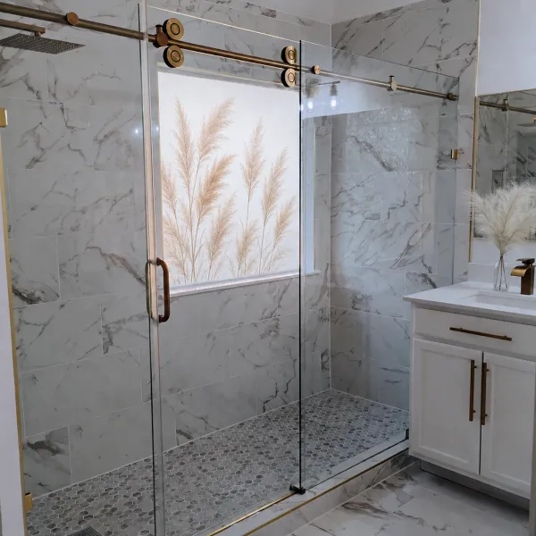 Sliding shower door with brass track and marble tile